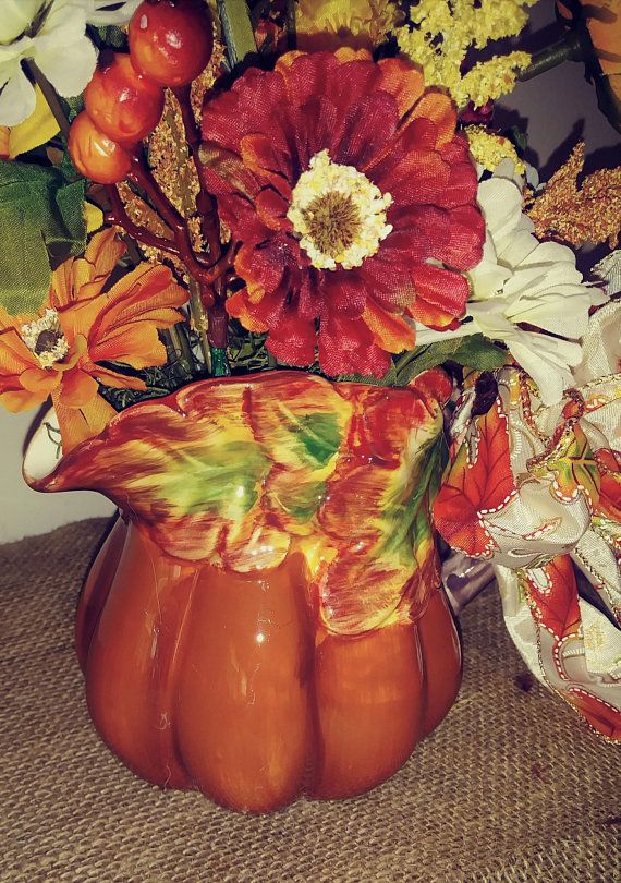 a vase filled with lots of flowers sitting on top of a brown cloth covered table