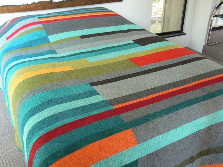 a bed covered in a multicolored blanket next to a window