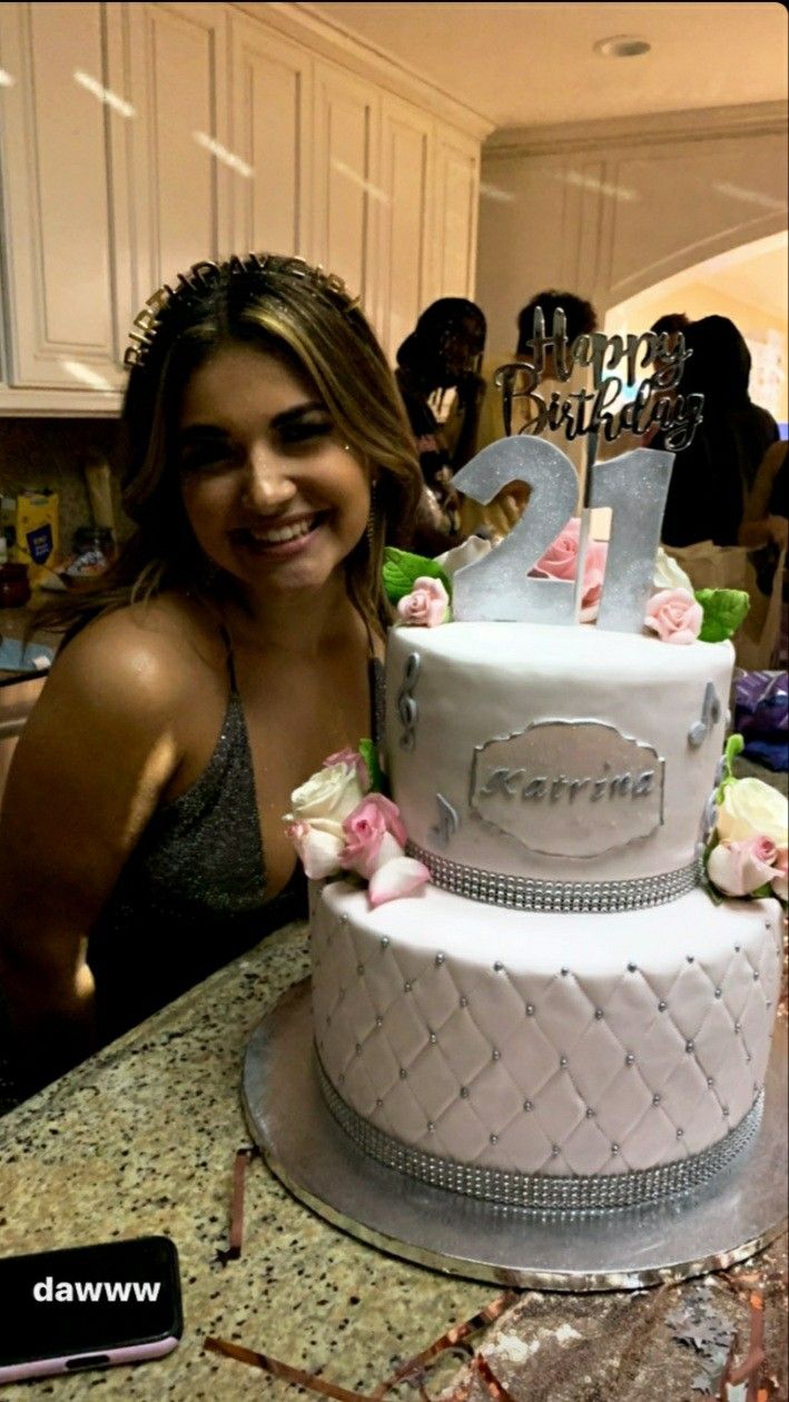 a woman standing in front of a two tiered cake