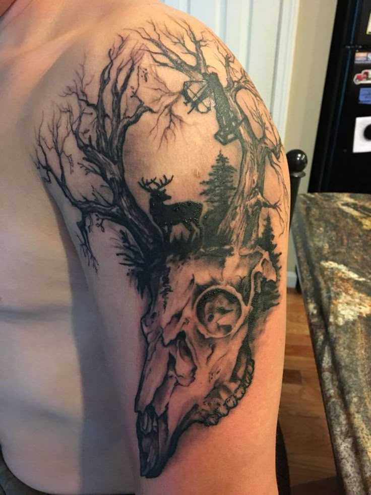 a man's arm with a deer skull and tree branches on the back of his shoulder