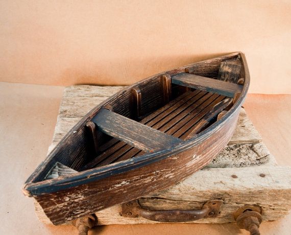 a small wooden boat sitting on top of a piece of driftwood next to a wall