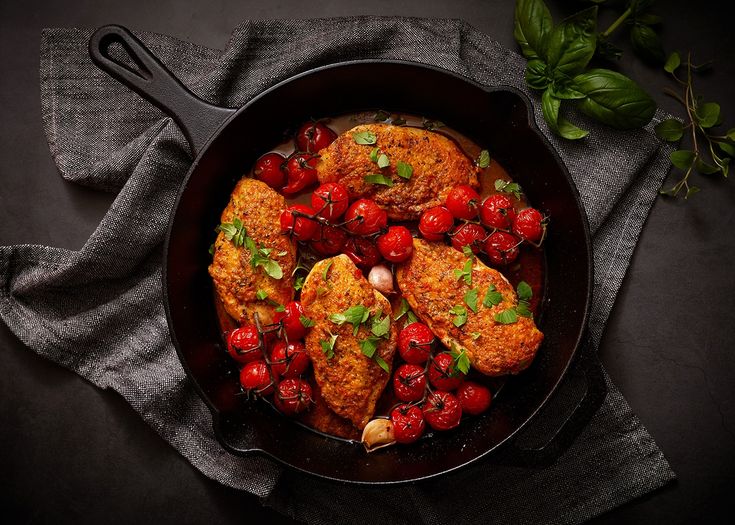 a skillet filled with chicken and cherry tomatoes