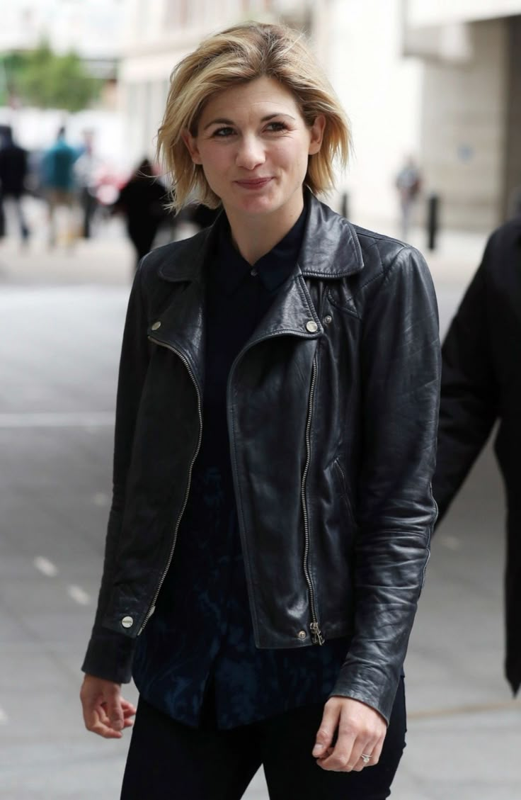 a woman in black leather jacket walking down the street