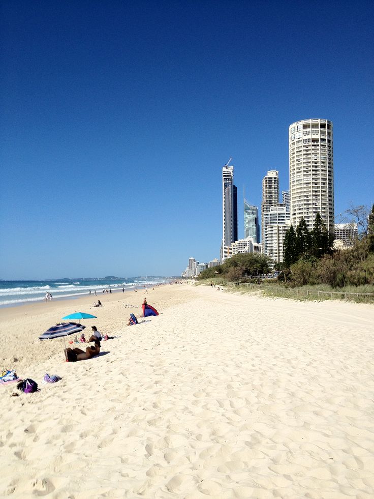 people are laying on the beach in front of tall buildings