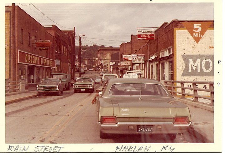 an old photo of cars driving down the street