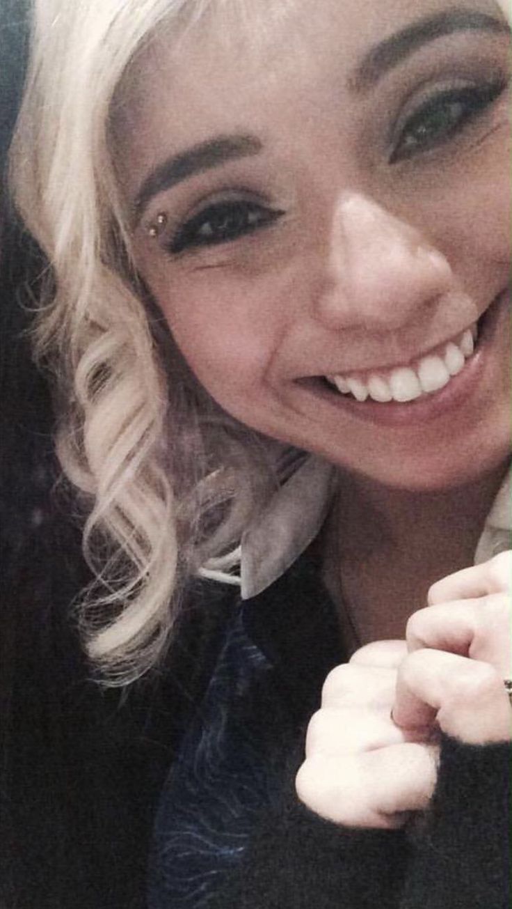 a woman with blonde hair is smiling and holding a cell phone to her ear while sitting in a car