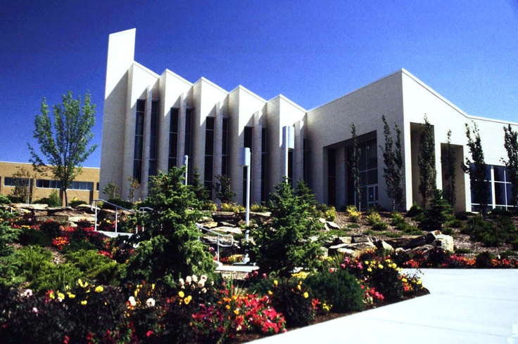 a large building with many windows and flowers in front of it on a sunny day