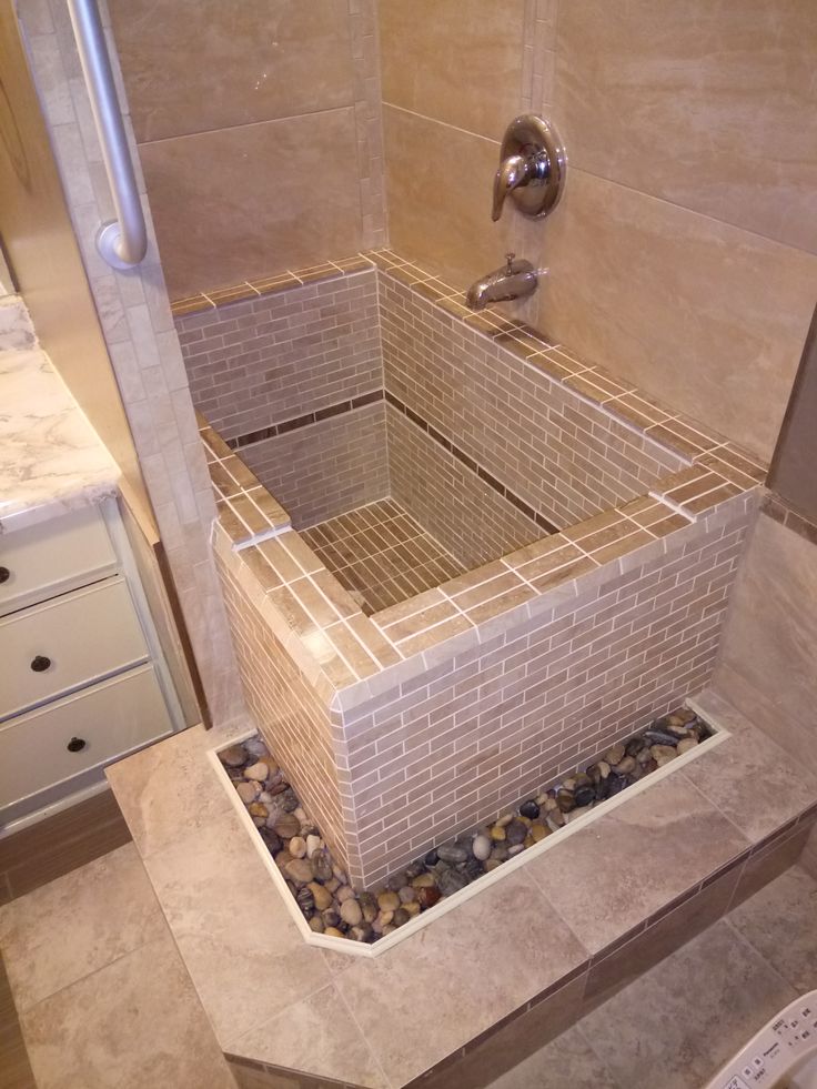 a walk in shower sitting inside of a bathroom next to a tiled wall and floor