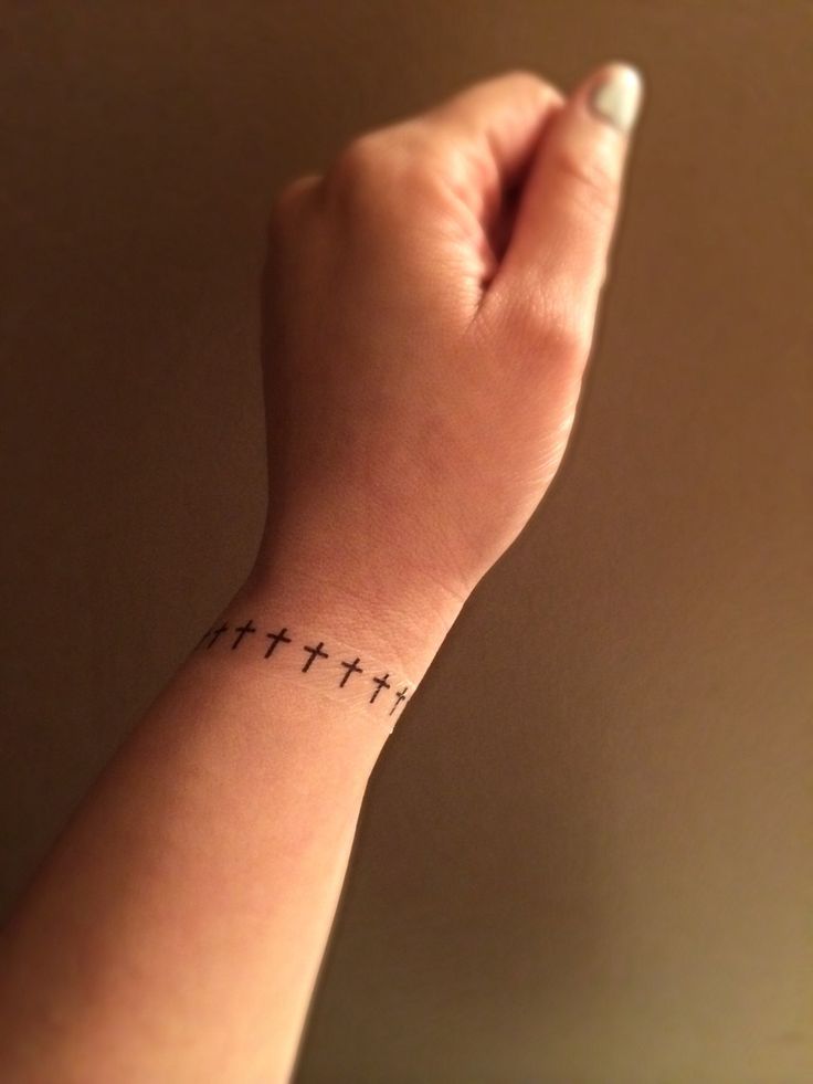 a woman's wrist with a small cross tattoo on the left side of her arm