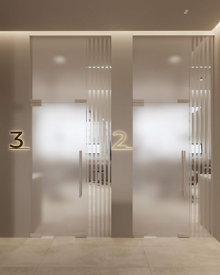 two glass doors with numbers on them in front of a white wall and floor area