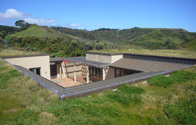 an aerial view of a house in the middle of a grassy area with mountains in the background