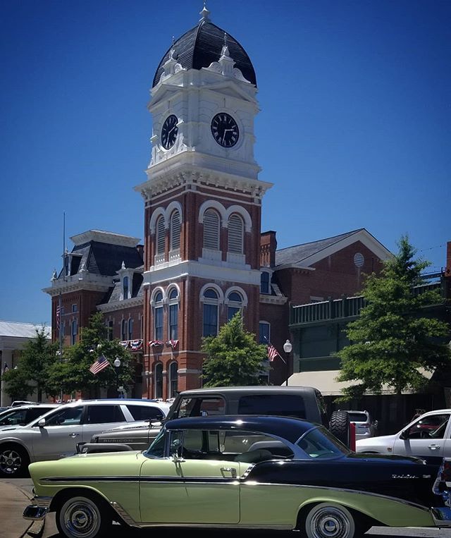 an old car parked in front of a clock tower