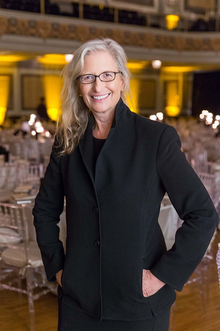 a woman standing with her hands on her hips in front of tables set up for an event