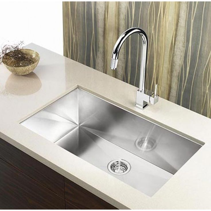 a stainless steel kitchen sink with faucet and soap dispenser next to it