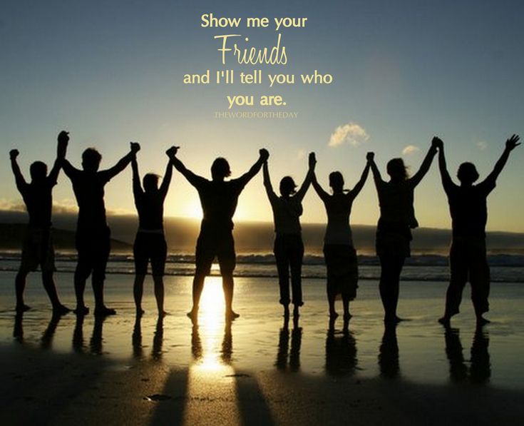 a group of people standing on top of a beach next to the ocean with their arms in the air