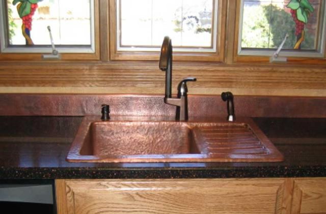 a kitchen sink with two faucets in the center and windows above it,