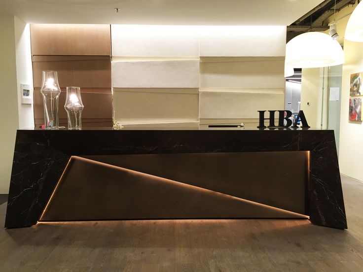 an office lobby with marble counter top and modern lighting fixtures on the wall behind it