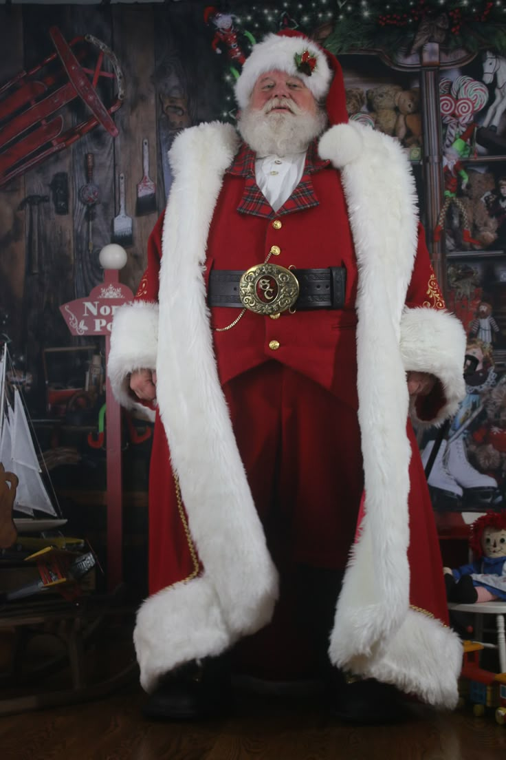 a man dressed as santa claus standing in front of a wall with pictures on it