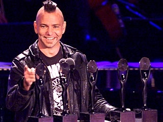 a man standing at a podium with microphones in front of him and an audience behind him