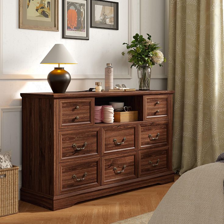 a wooden dresser sitting in front of a window with pictures on the wall behind it