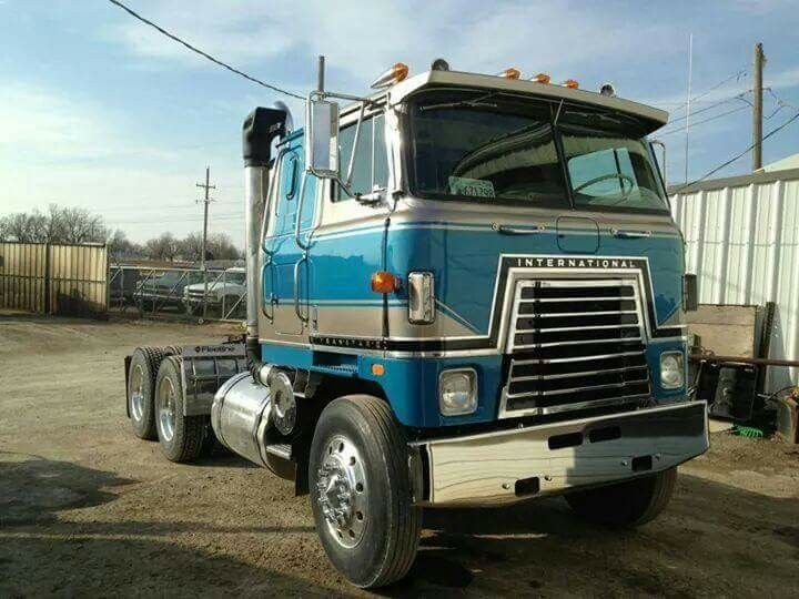 a large blue truck parked on top of a dirt field