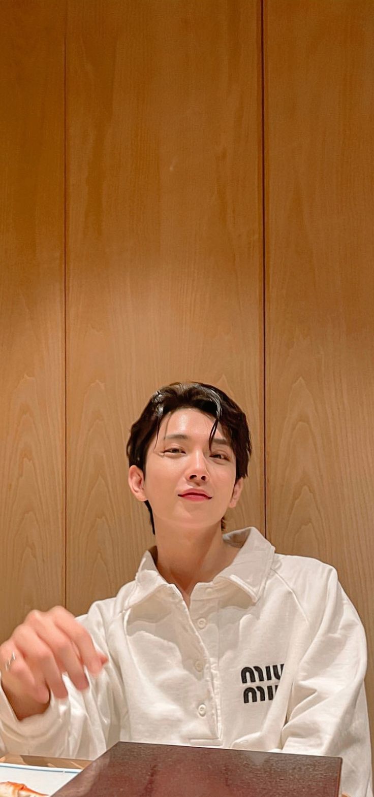 a young man sitting at a table with food in front of him and looking up