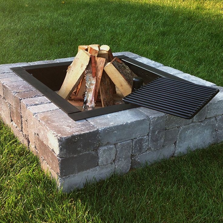 a fire pit sitting on top of a lush green field