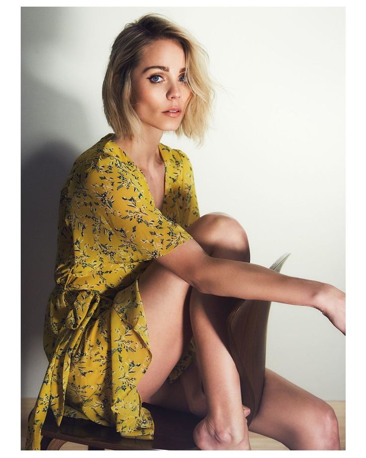 a woman sitting on top of a wooden chair wearing a yellow dress and holding a knife