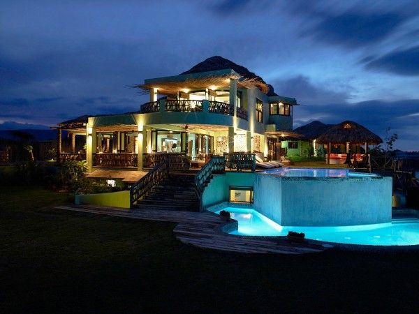 a large house with a swimming pool in the front yard at night, and steps leading up to it