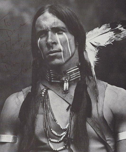 an old photo of a native american man with feathers on his head and nose ring