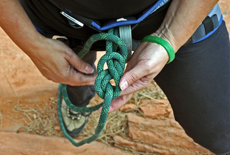 a person tying a green rope with their hands