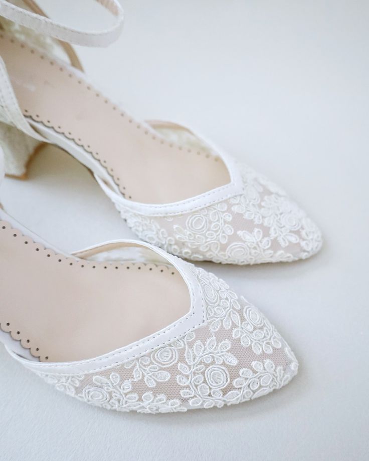 a pair of white shoes with lace and bows on the toes are sitting next to each other