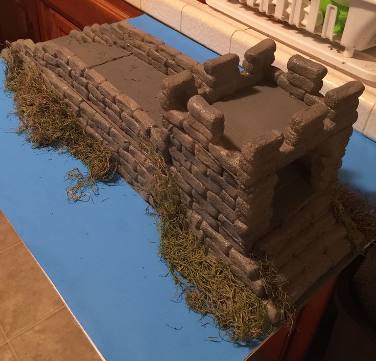 a cake made to look like a stone house with grass growing out of the roof