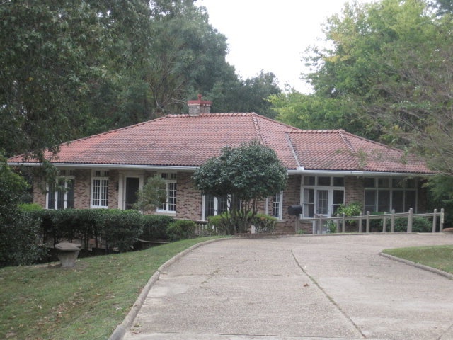 a driveway leading to a house with trees in the background