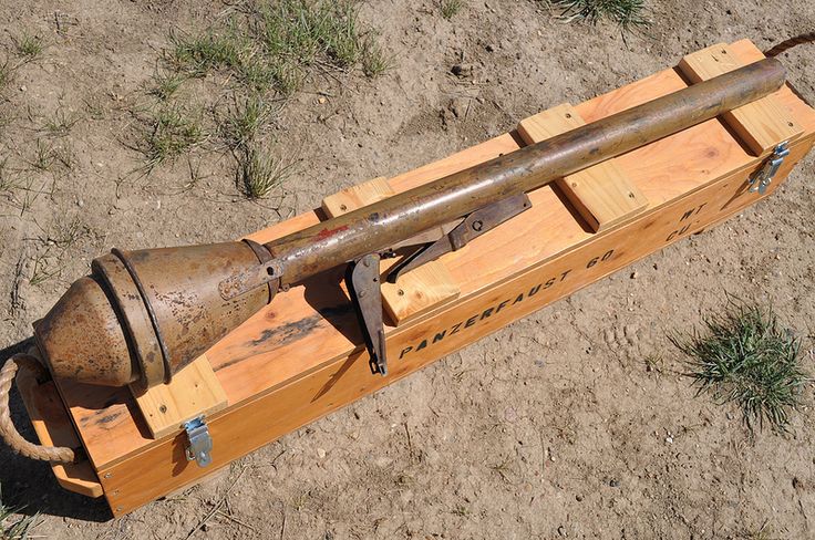 an old metal object sitting on top of a wooden crate in the dirt and grass