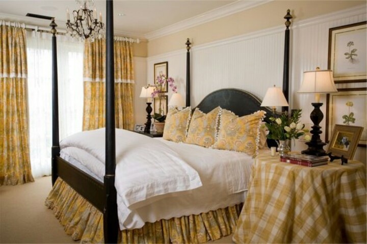 a bedroom with four poster bed and yellow curtains