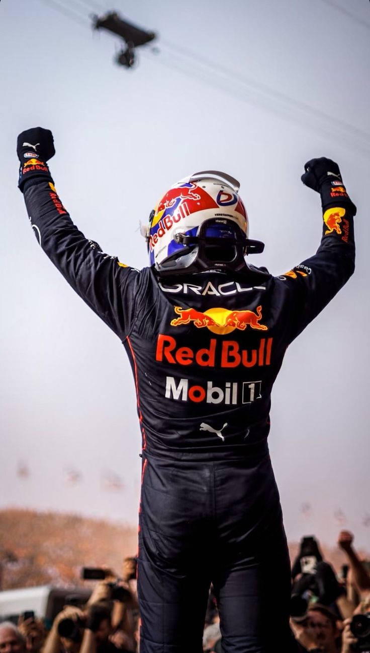 a man with his arms in the air and wearing a red bull racing suit on