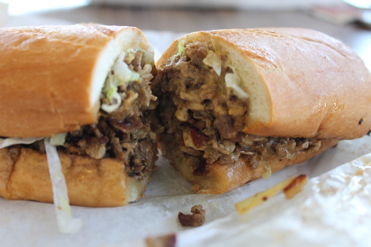 a sandwich cut in half sitting on top of a piece of wax paper next to a knife