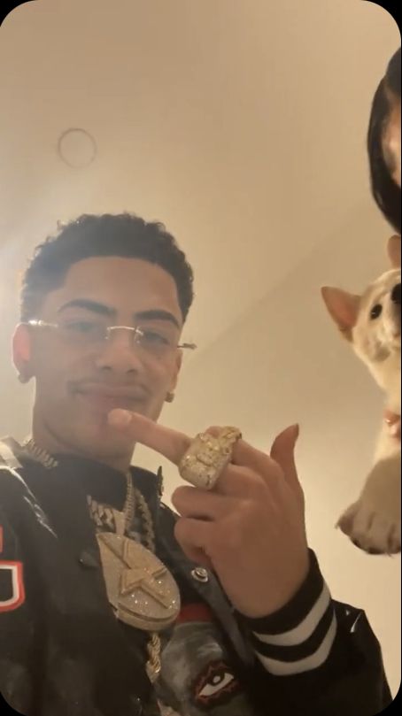 a man with glasses and a cat in the background taking a selfie while holding something up to his mouth