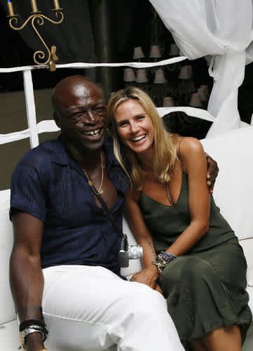 a man and woman are sitting on a white bench smiling at the camera while posing for a photo