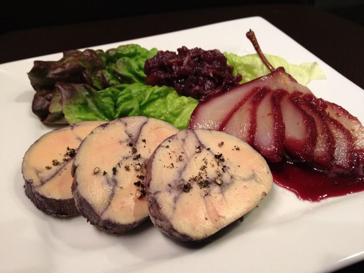 a white plate topped with meat covered in sauce next to lettuce and salad