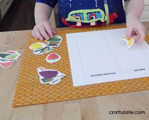 a young child is cutting out some food pictures on a piece of paper with scissors