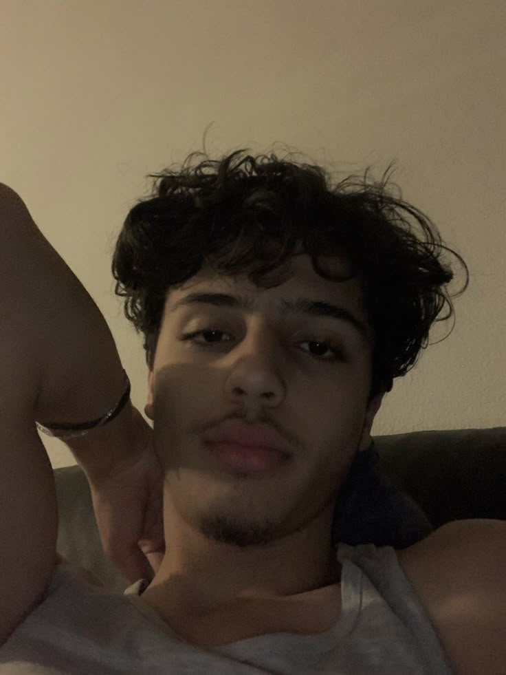 a young man sitting on top of a couch next to a wall with his arm up