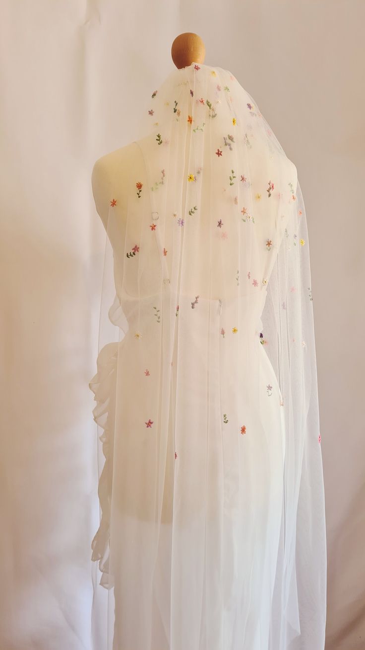 a long wedding veil with colourful tiny hand embroidered flowers fading down from the comb. Embroidered Wildflower Veil, Flowery Wedding Veil, Floral Wedding Veil Colorful, Colourful Flower Wedding, Colourful Floral Wedding, Flower Veil Wedding, Bridal Shower Bride Outfit, Wedding Veil Ideas, Embroidered Wedding Veil