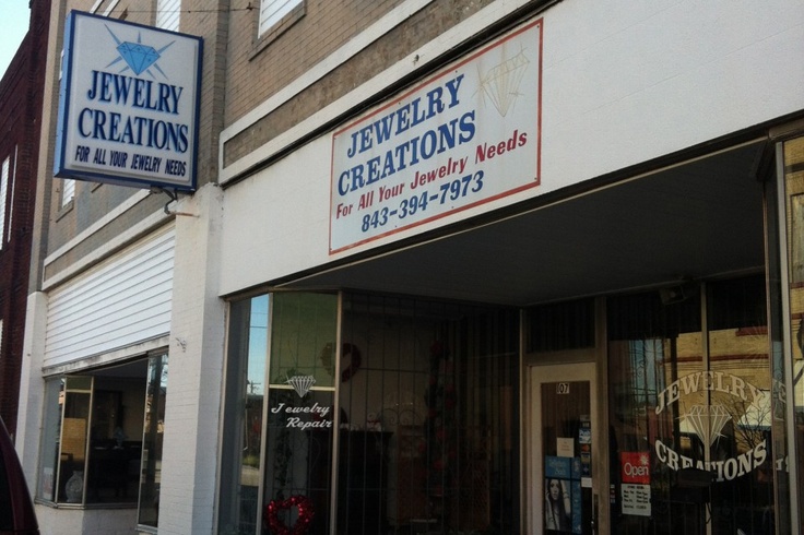 a jewelry store with two signs on the side of it's doors that read jewelry creations