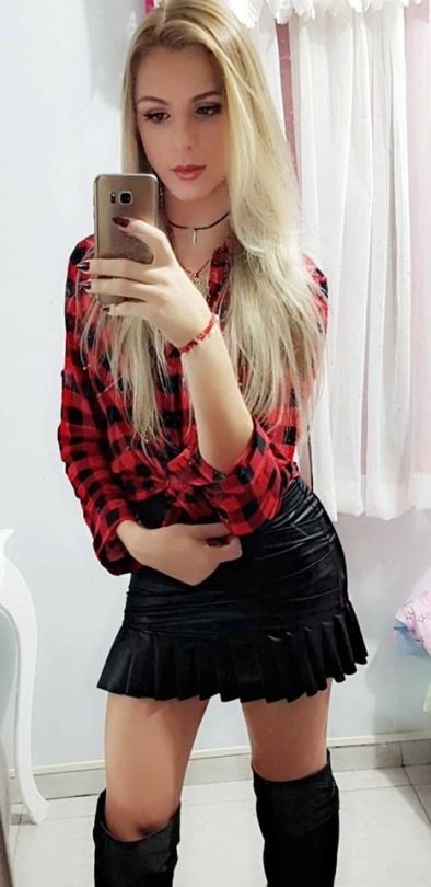 a woman taking a selfie in front of a mirror wearing thigh high boots and a plaid shirt