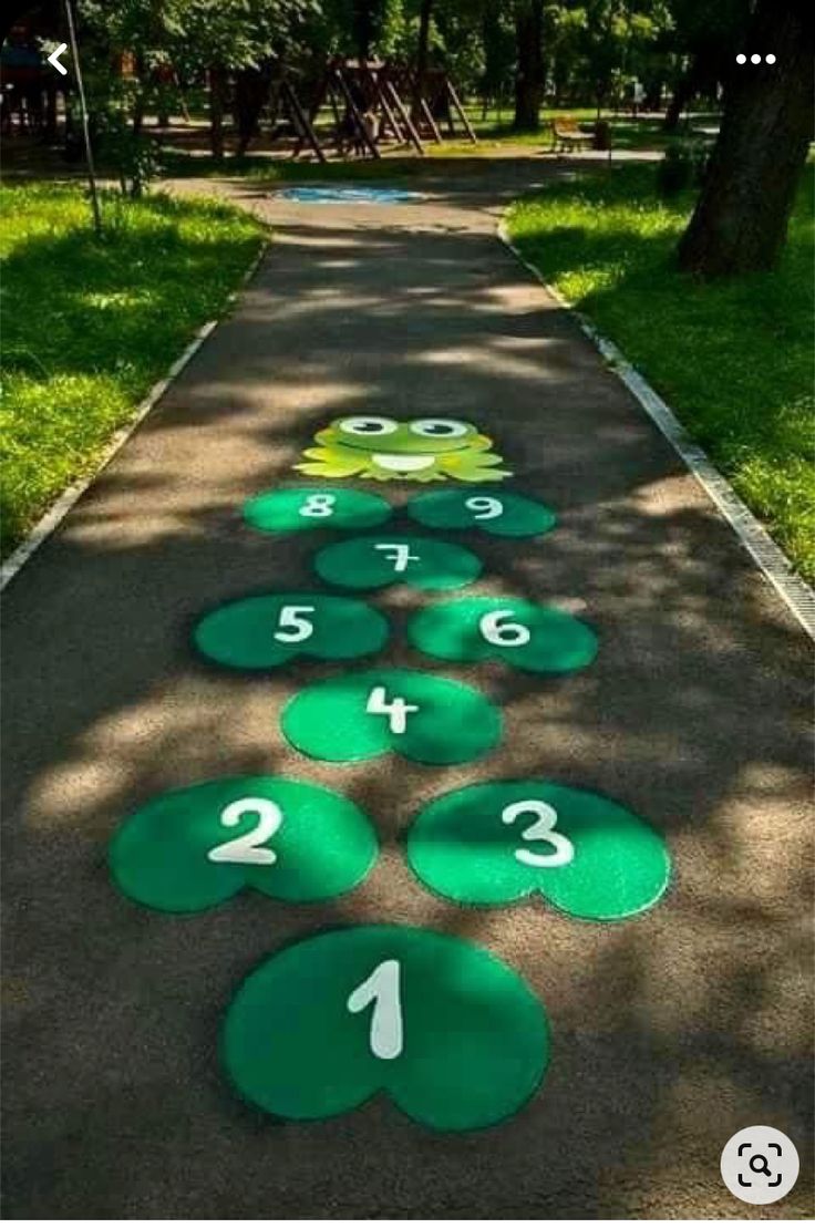 a number line painted on the sidewalk with numbers in green and white, next to a tree