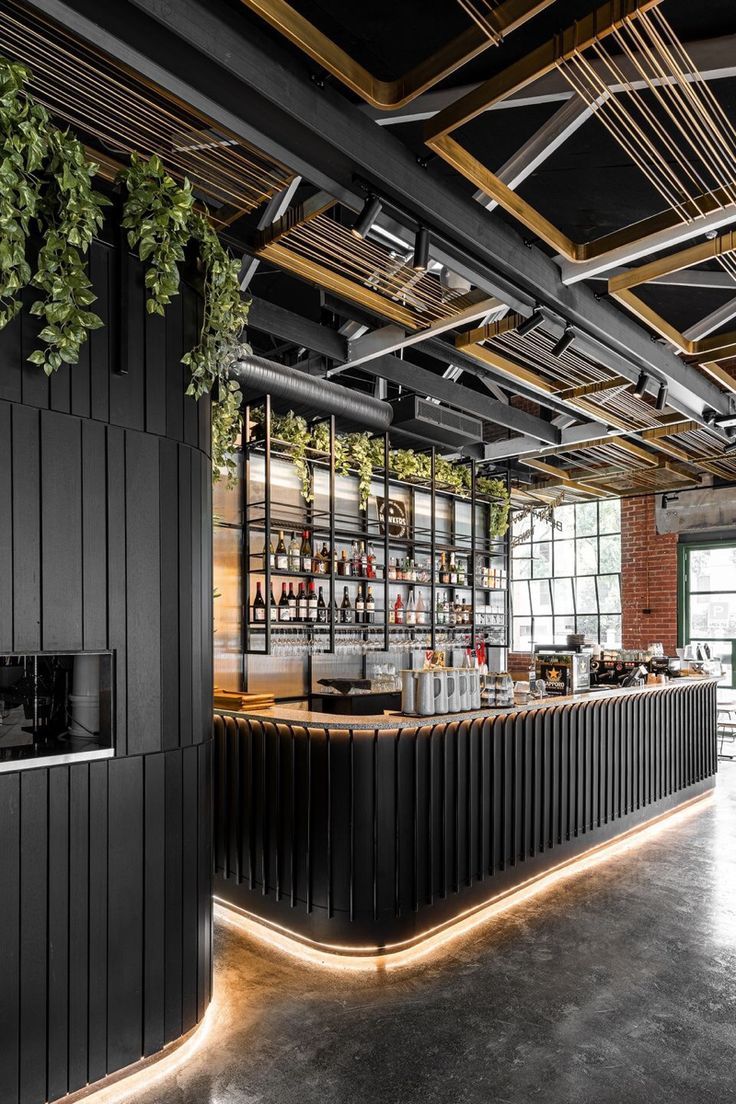 the bar is decorated in black and has plants growing on the wall, along with an open fire place