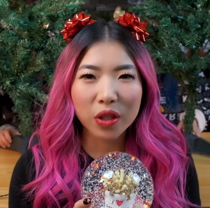 a woman with pink hair holding up a snow globe