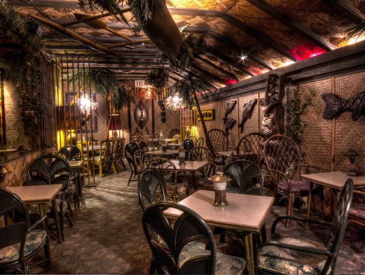 a restaurant with many tables and chairs in the middle of an indoor area that has plants growing on the walls